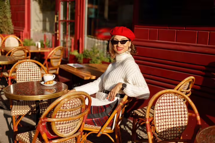 Chic woman in red beret enjoying coffee at a cozy Parisian café, capturing the essence of hidden Parisian charm and style.