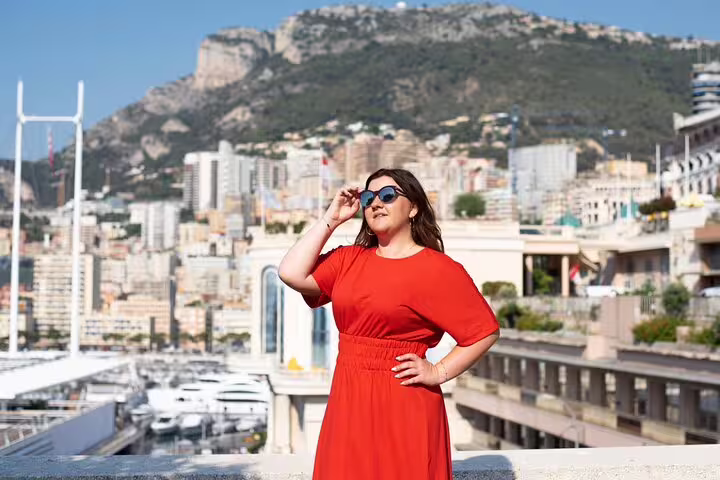 Woman in red dress posing with scenic Cannes cityscape and mountains in the background during a private photoshoot.