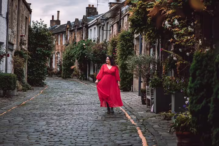 Woman in red dress on Dean Village cobblestone lane during private Edinburgh photoshoot with professional photographer