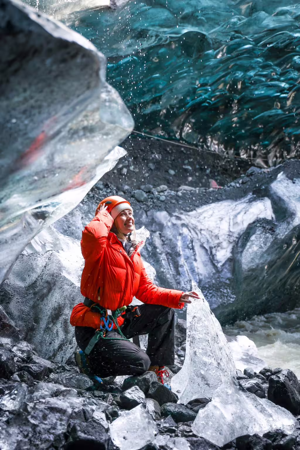 Smiling woman in red jacket and helmet exploring a sapphire ice cave on an early bird guided tour in Iceland