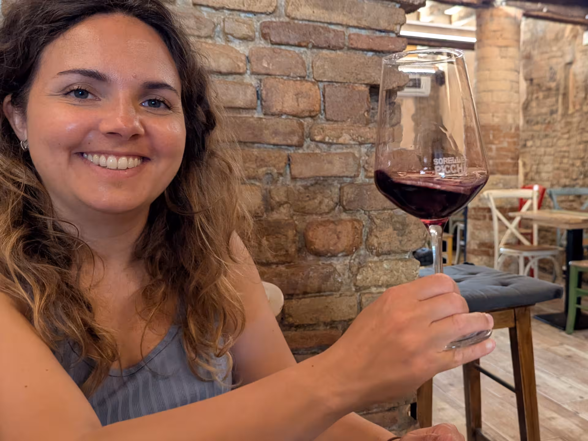 Smiling woman enjoying a glass of red wine during a Parma wine tasting tour, showcasing local flavors.