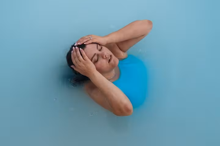 Woman in blue swimsuit relaxing in the milky blue waters of Iceland's Blue Lagoon