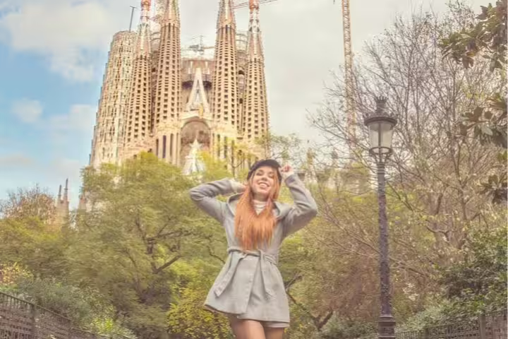 Woman joyfully posing in front of Sagrada Familia, highlighting Barcelona's iconic architecture on Montserrat tour with hotel pickup.