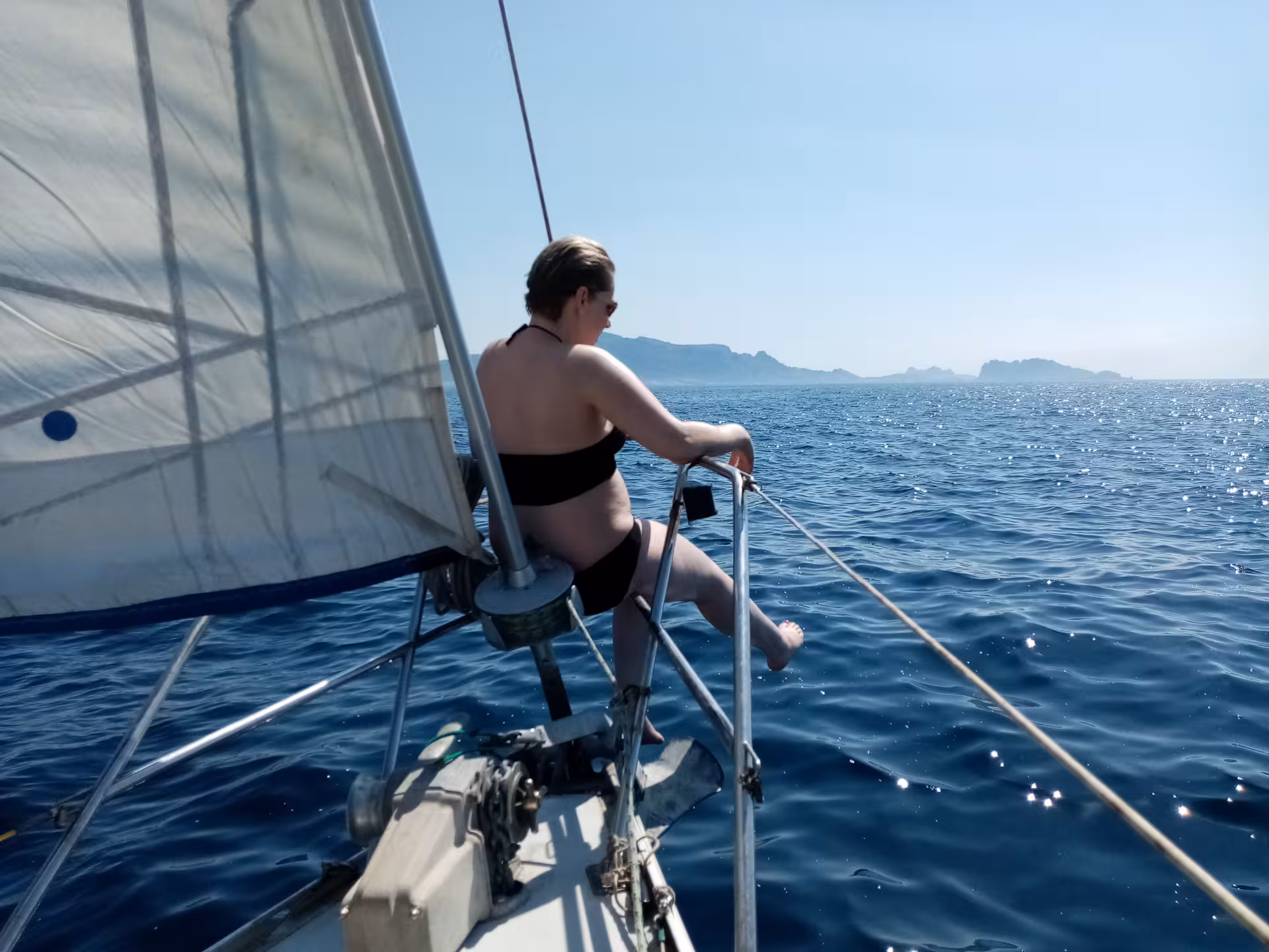 Woman relaxing on sailboat bow over blue Mediterranean Sea, island views on 3-day boating and snorkeling trip