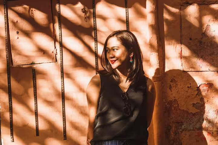 Smiling woman enjoying the play of shadows on a sunny day in Marrakesh during a private vacation photo shoot.