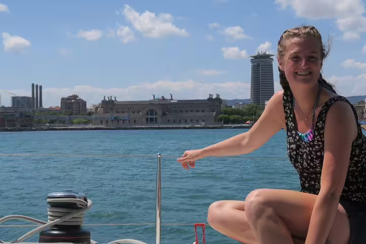 Woman enjoying a sunny day on a small group cruise with food and drinks, scenic views of city skyline in the background.
