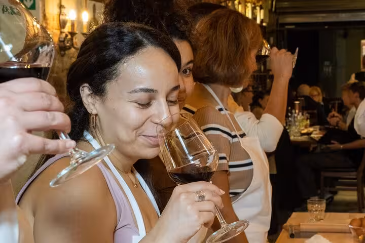Woman savoring red wine aroma at Florence cooking class, highlighting the delightful wine-tasting experience.