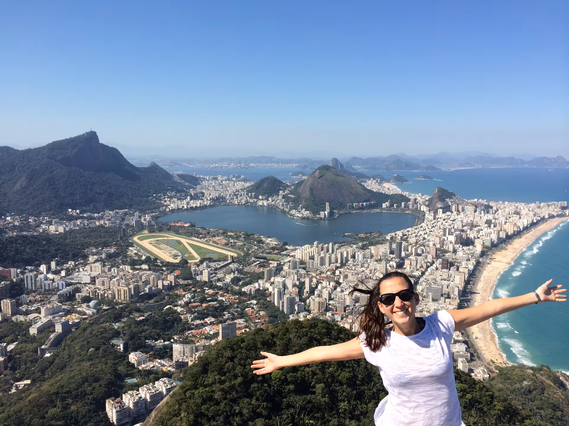 Woman with open arms atop Two Brothers Hill, capturing Rio de Janeiro's breathtaking city and ocean views.