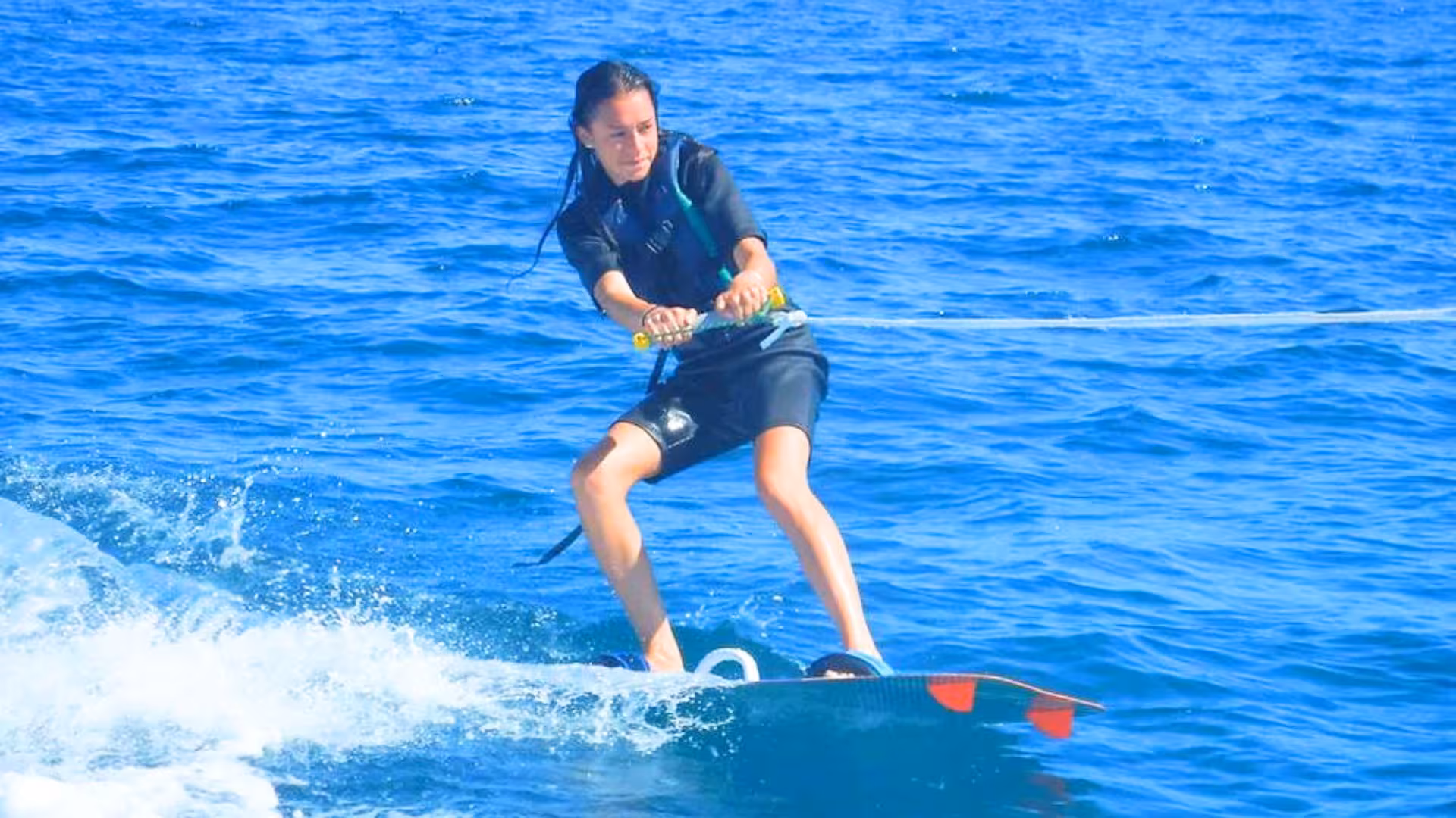 Woman skillfully wakeboarding on the vibrant waters of Golfo degli Angeli, Cagliari.
