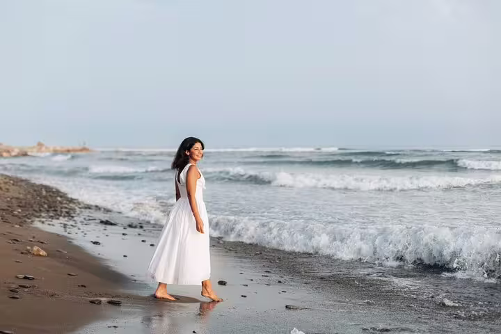 Woman in a white dress walking along the beach during a private photoshoot in Marbella.