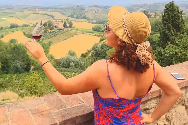 Woman enjoying wine with stunning Tuscan landscape, embodying the essence of a day trip from Rome.