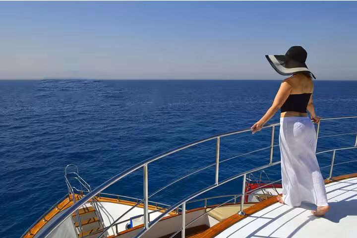 Woman on yacht deck cruising Red Sea to Eden Island from Hurghada, relaxing on day trip with lunch and water sports