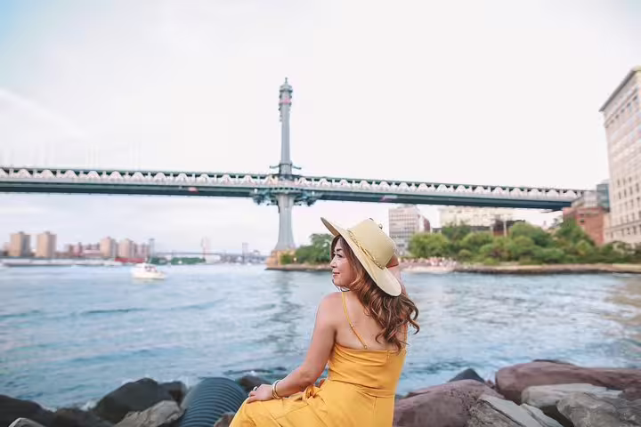 Woman in yellow dress by Manhattan Bridge, enjoying personal photo tour in NYC.
