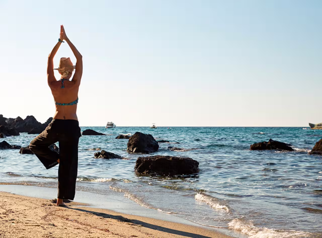 Woman doing yoga on Ischia beach near Poseidon Gardens, perfect add-on to thermal spa entrance ticket