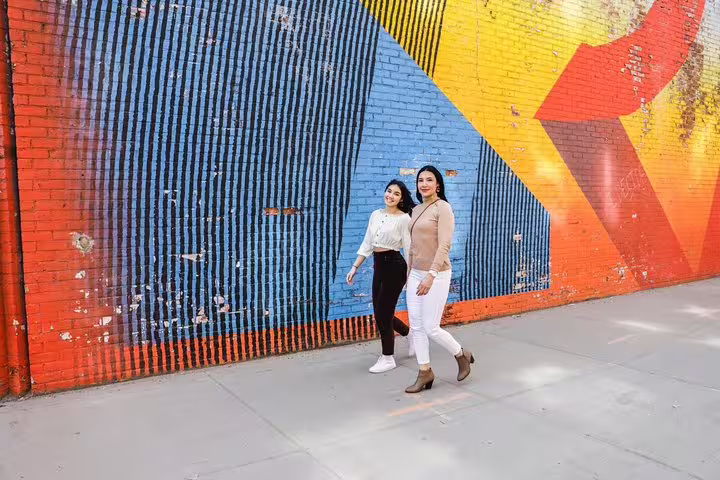 Two women strolling by vibrant street art in Brooklyn, capturing colorful moments on a New York personal photographer tour.