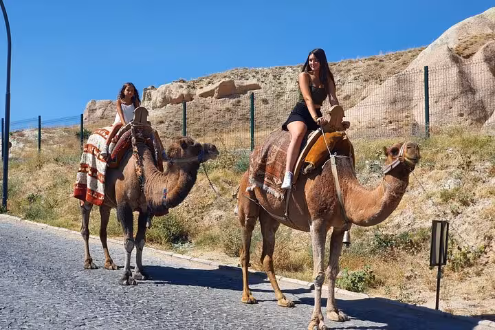 Women riding camels in Cappadocia on a private tour with English-speaking guide and luxury vehicle transfer