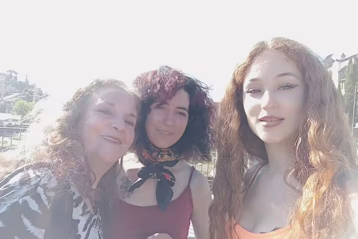 Three women smiling together outdoors on a sunny day during a Rome walking tour