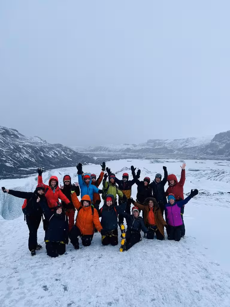 Group of adventurous women celebrating atop a snowy Icelandic glacier during a women-only winter expedition.