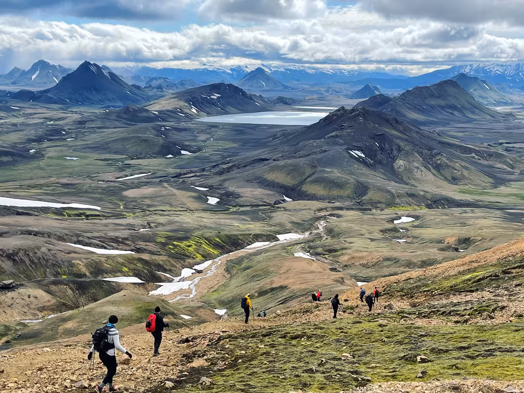Women hikers trekking the scenic Laugavegur Trail in Iceland, surrounded by vast landscapes and distant mountains.