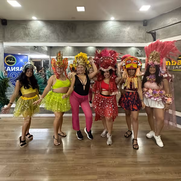 Group of women in vibrant samba costumes posing in a dance studio for an all-levels samba class experience.