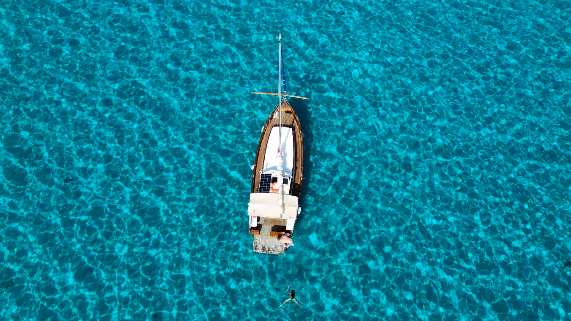Aerial view of a wooden boat on crystal-clear waters during a Stintino excursion to Asinara Island.