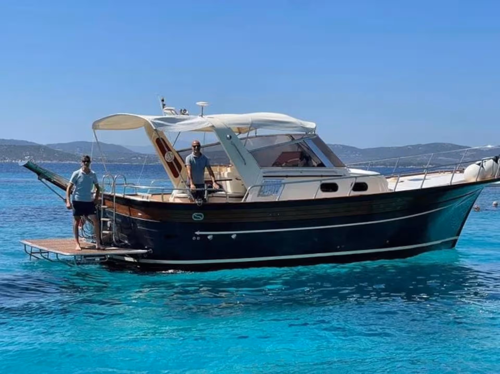 Wooden boat tour in southern Corsica showcasing a classic vessel on crystal-clear blue waters near La Maddalena.