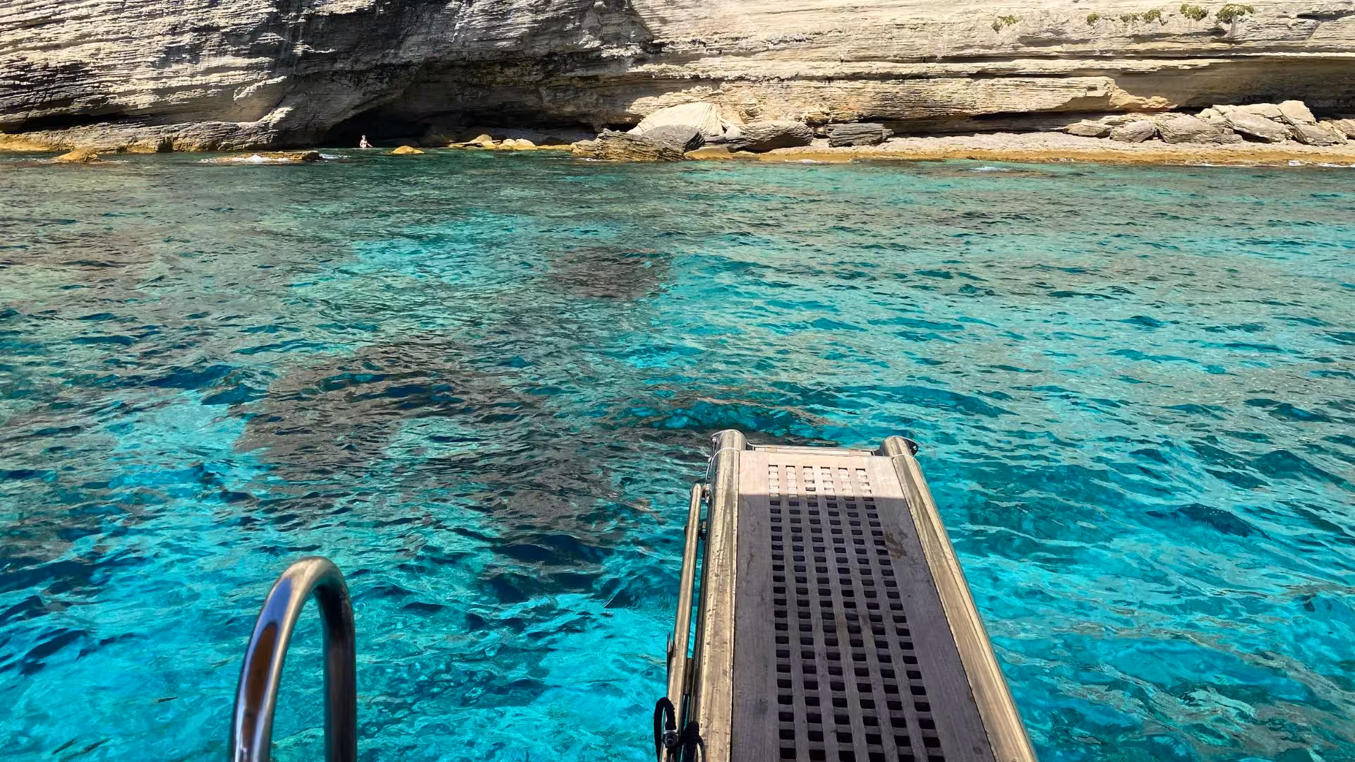 Turquoise waters and rugged cliffs near a boat dock in Southern Corsica, perfect for wooden boat explorations.