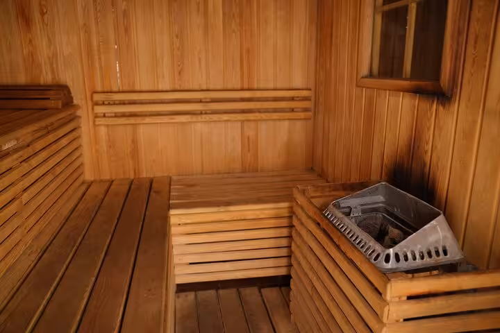 Wooden sauna room with heater and benches at Sharm El Sheikh spa, part of VIP solo massage experience