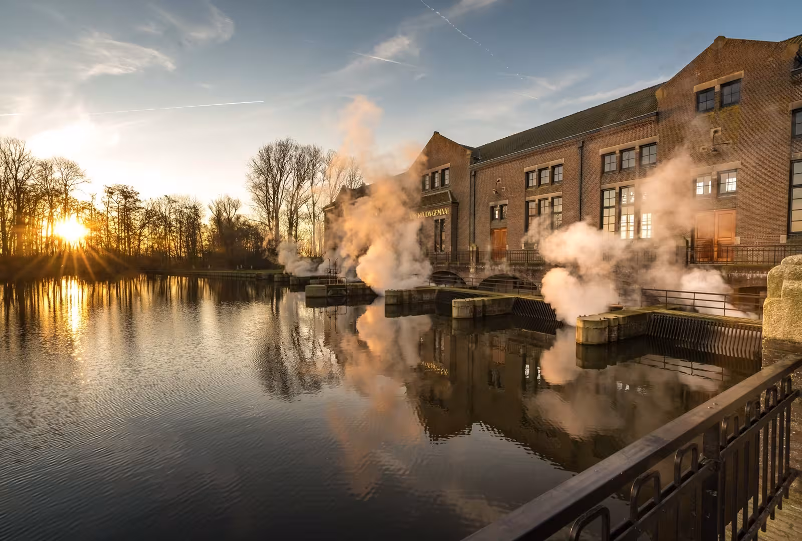 Wouda Pumping Station UNESCO site at sunset, steam rising over water on a private tour from Amsterdam