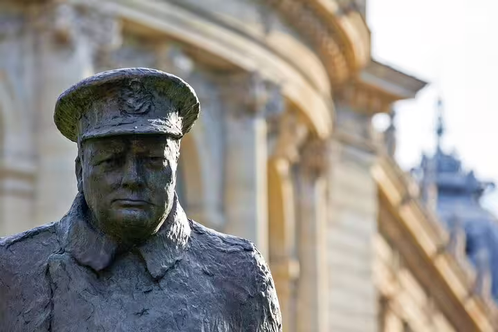 Bronze statue of WWII military figure in uniform cap near classical Parisian building