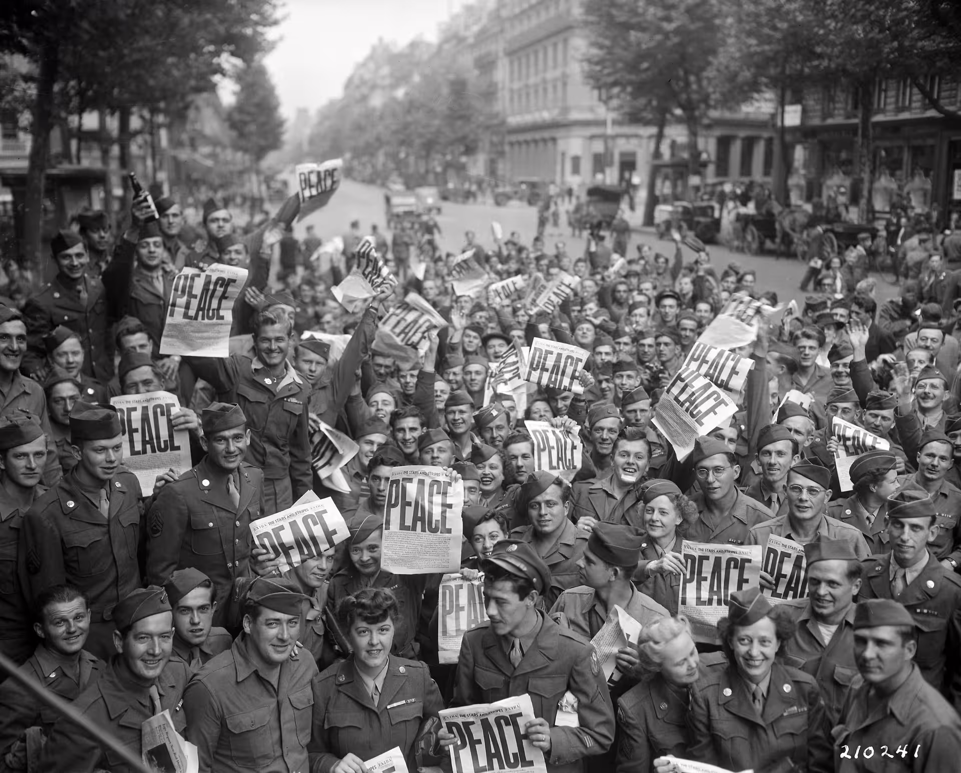 WWII soldiers celebrating peace in Paris streets holding Stars and Stripes newspapers at liberation