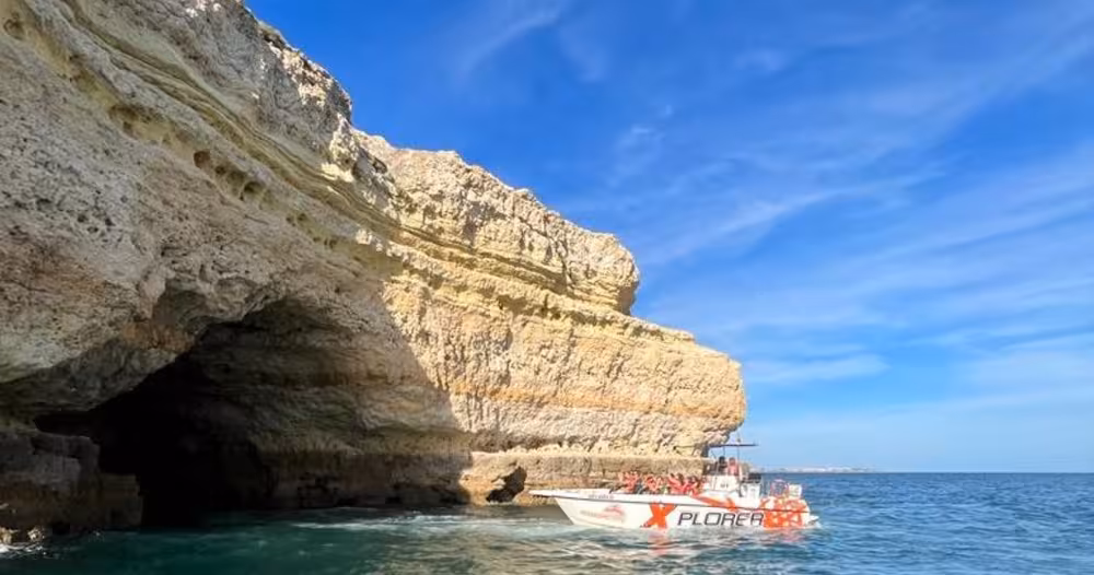 X Plorer Benagil caves cruise boat gliding by dramatic Algarve sea cliffs on a sunny Portugal dolphin watching tour