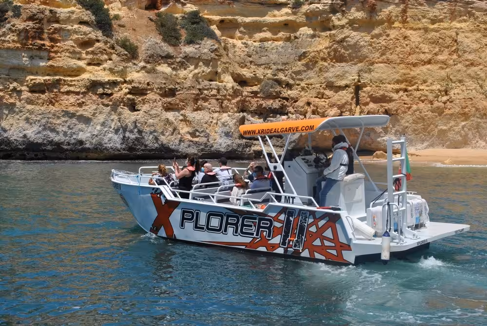 Tourists on X Plorer boat cruising close to Algarve limestone cliffs on a guided Benagil caves and dolphins excursion