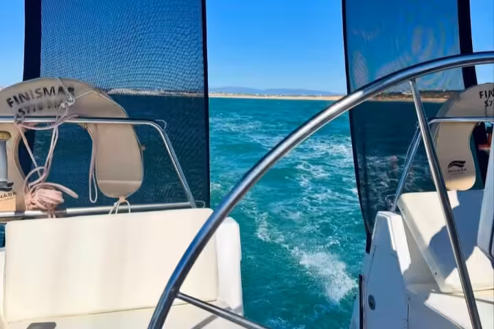 View from YACHT FINISMAR's deck, showcasing the helm and ocean waves on a sunny day adventure tour.
