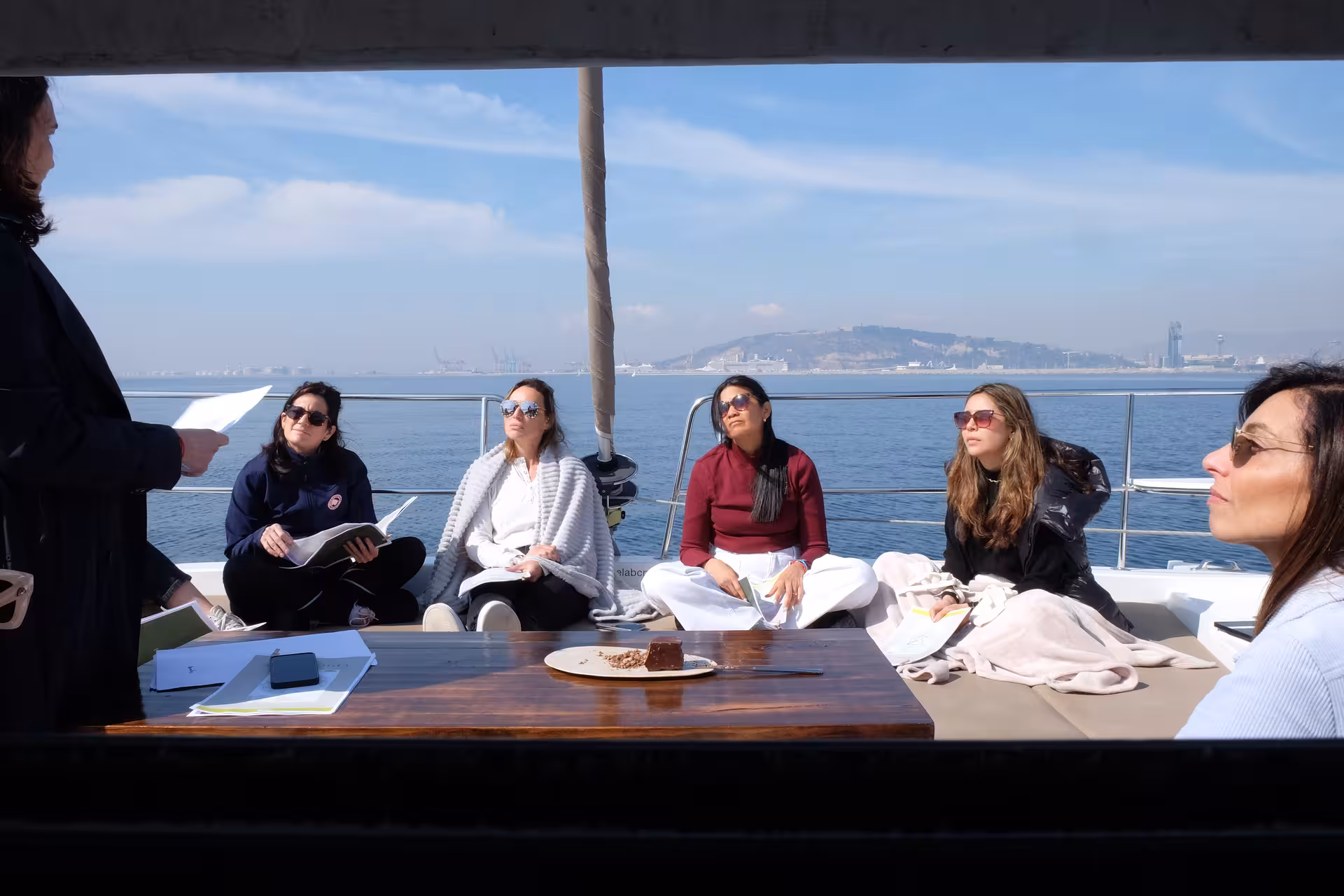 Guests seated on a yacht deck enjoying a guided tea ceremony workshop with ocean views and tasting notes