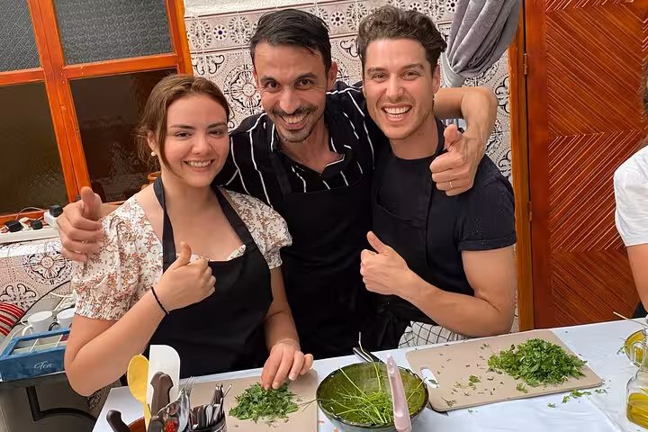 Happy participants in Yassine's cooking class enjoying chopping herbs, ready for a Moroccan culinary experience.