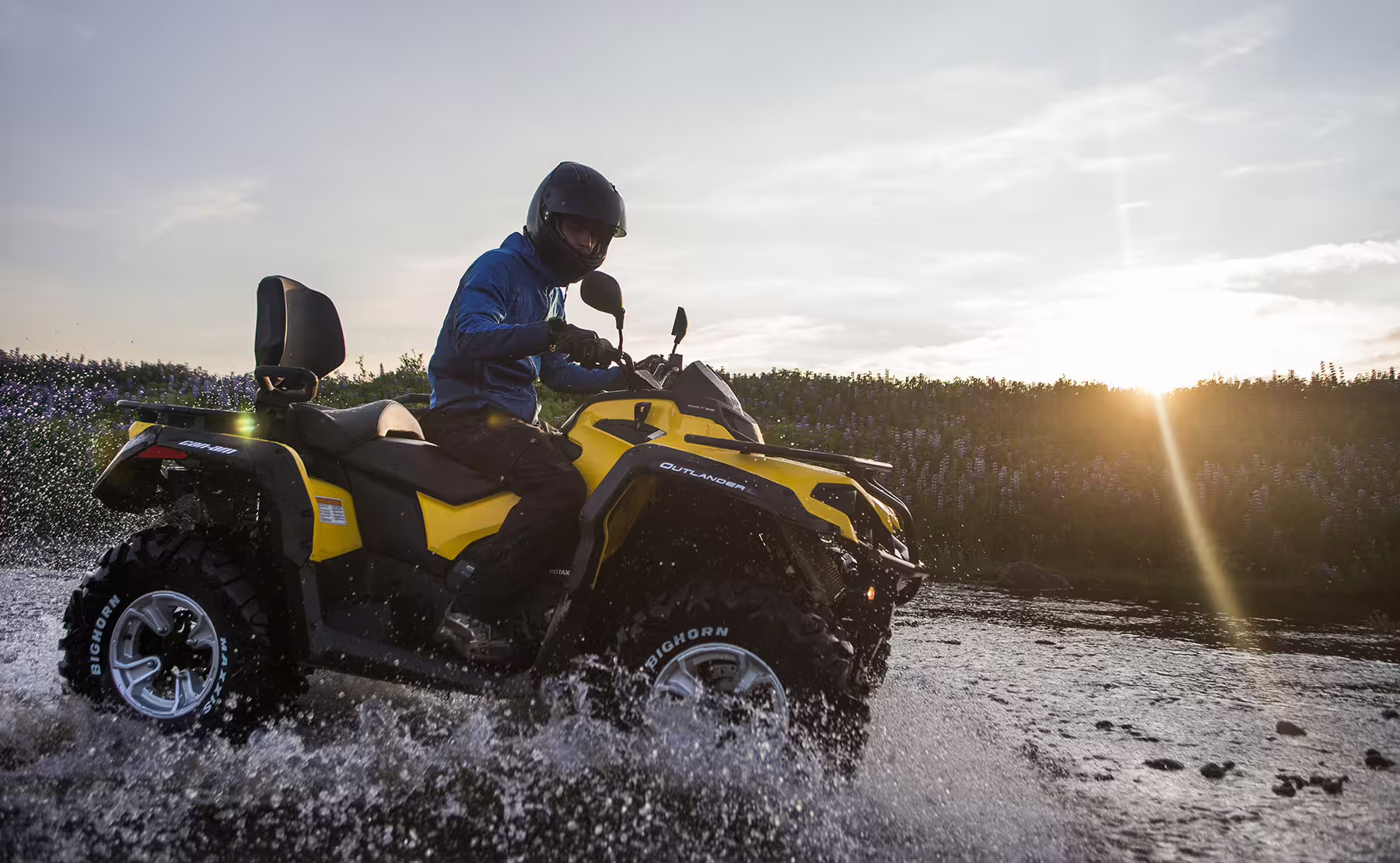 Adventurer on a yellow ATV splashing through water during a scenic 1-hour Reykjavik Peak tour at sunset.