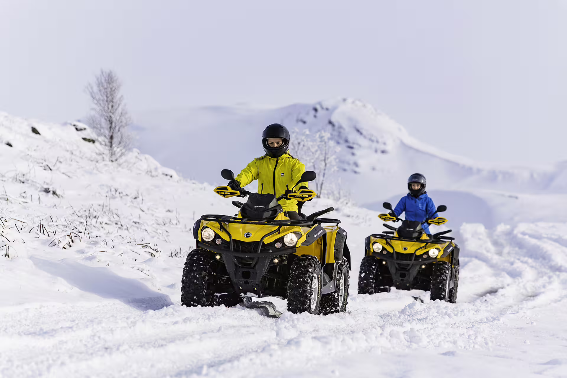 Adventurers riding yellow ATVs on snowy terrain, showcasing thrilling winter off-road tour experience for ATV and caving enthusiasts.