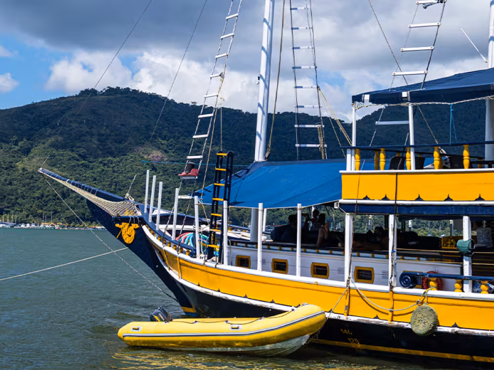 Yellow and blue boat anchored with inflatable dinghy during a scenic five-hour caipirinha boat tour.