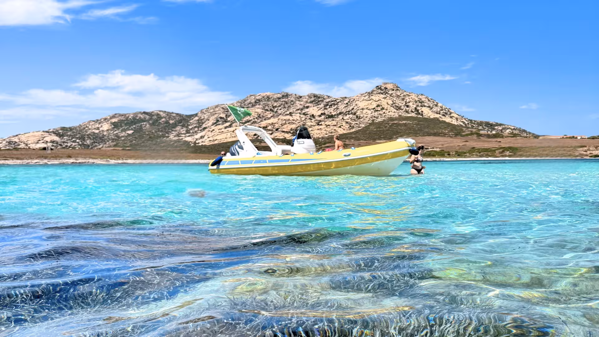 Yellow dinghy floating on crystal-clear waters near Asinara Island, showcasing vibrant marine life and scenic landscapes.