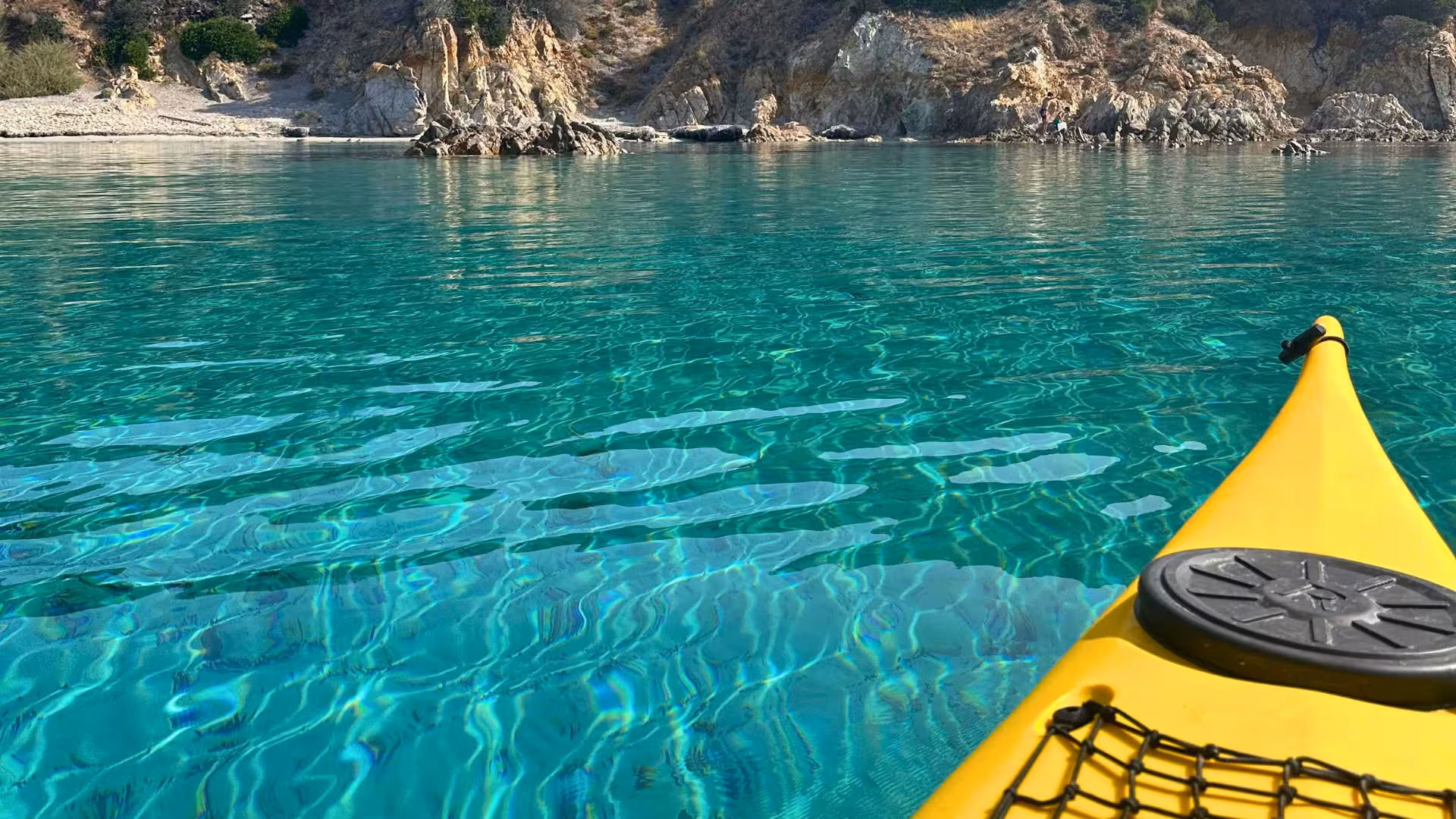 Yellow kayak on crystal-clear waters near rocky cliffs at Tuerredda, offering breathtaking views in Sardinia.
