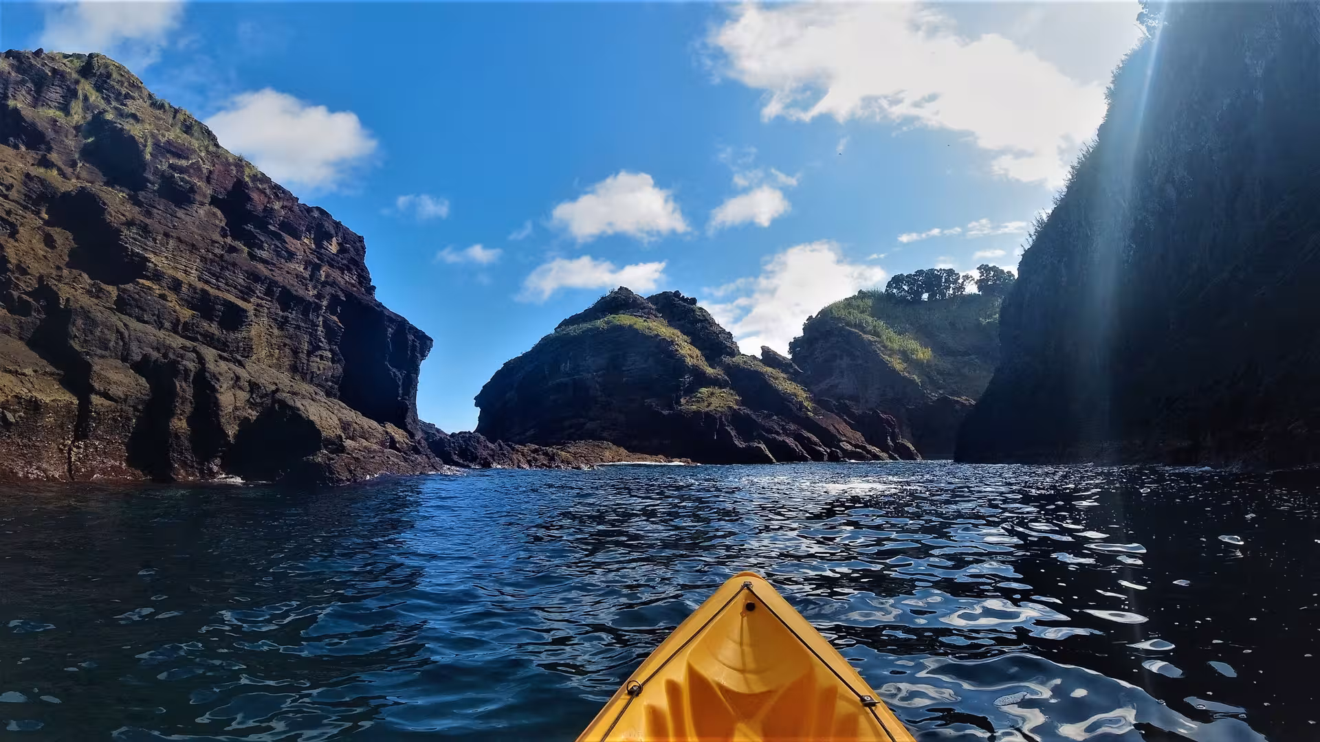 POV from a yellow kayak paddling between volcanic cliffs near Vila Franca do Campo, São Miguel Azores