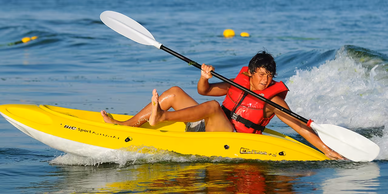 Solo kayaker in Fuzeta, Ria Formosa, paddling a yellow sea kayak through gentle surf on an Algarve tour