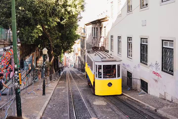 Iconic yellow tram descends a steep street in Lisbon's Chiado, ideal for a scenic tuk tuk tour of Bairro Alto.