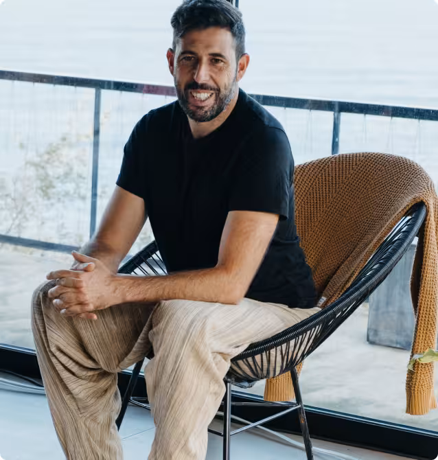 Smiling man sitting relaxed on a wicker chair on a balcony with ocean view