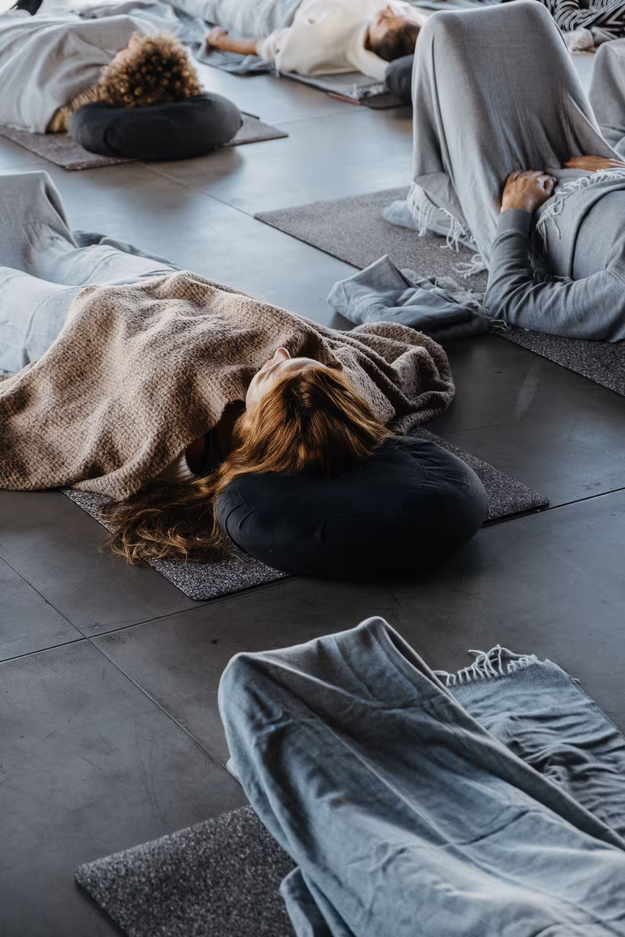 Group of participants lying on yoga mats with blankets during a meditation retreat session