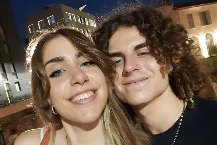 Two young tourists smiling together at night in Milan city center