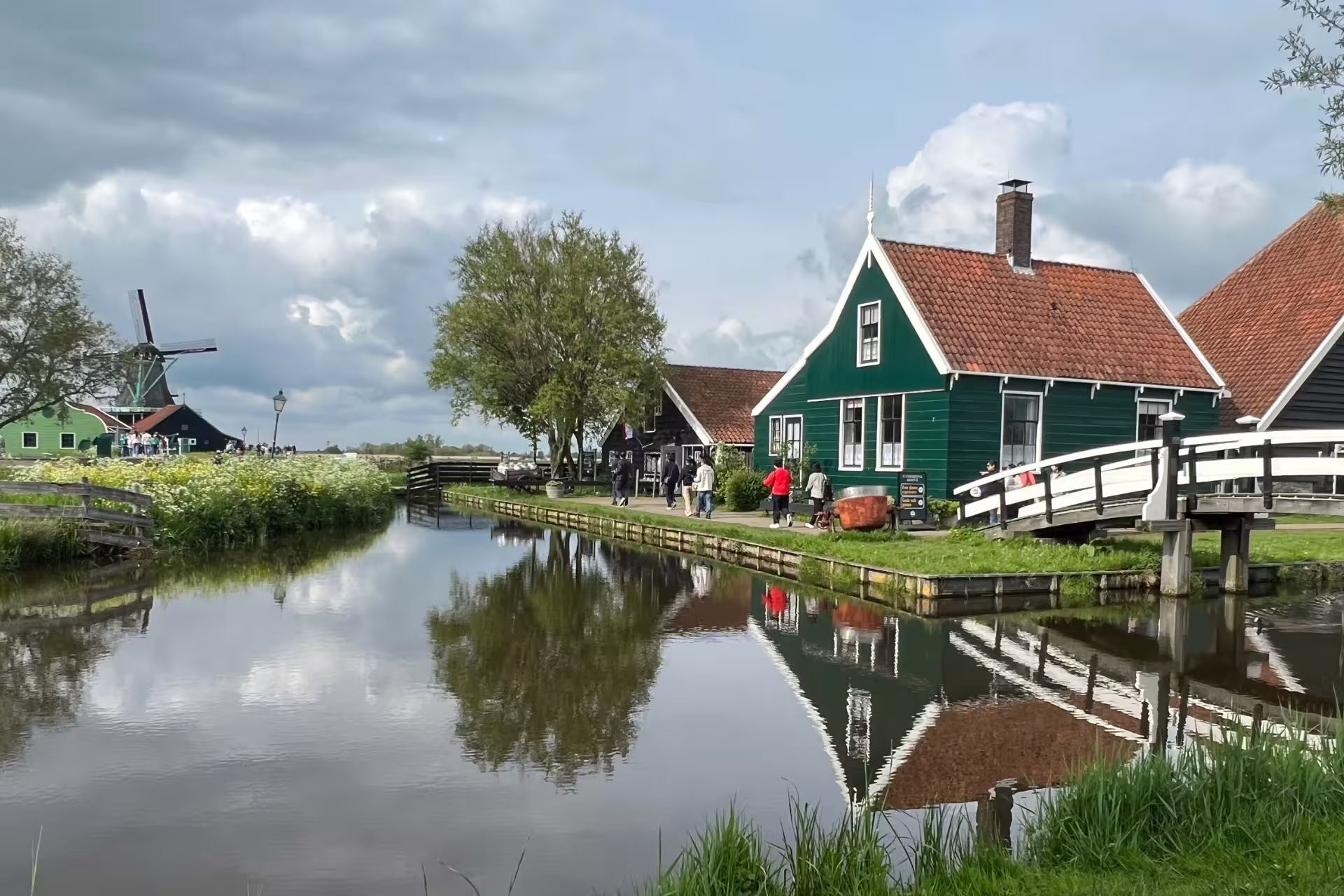 Zaanse Schans green house and canal with bridge and windmill, stop on Amsterdam Giethoorn tour with cruise