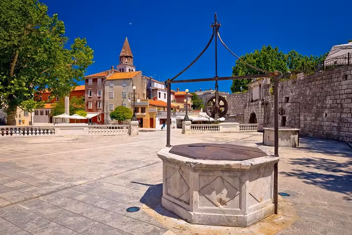 Historic Zadar square with stone well and old town walls, prelude to Plitvice Lakes private transfer to Zagreb