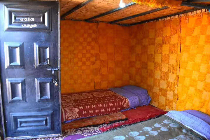 Simple Zagora desert camp room with floor mattresses and rugs on a private 2-day tour from Marrakech